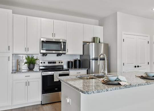 A modern kitchen with white cabinets and stainless steel appliances.