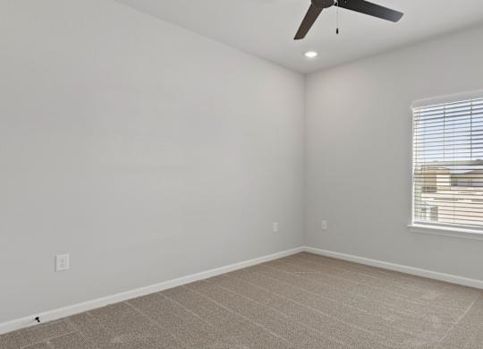 A room with a ceiling fan and a window with blinds.