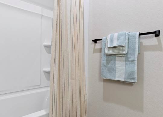 A white bathroom with a towel rack and a shower curtain.