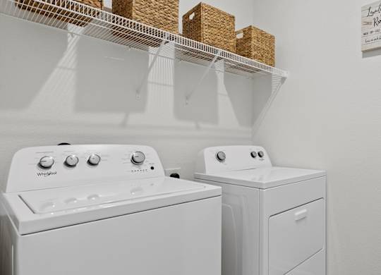 Two white washing machines in a laundry room.