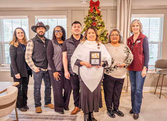 A group of people are posing for a photo in a room with a Christmas tree in the background.