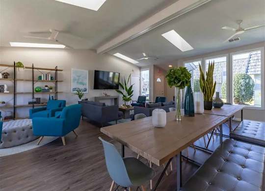 A modern living room with a large wooden table and blue chairs.