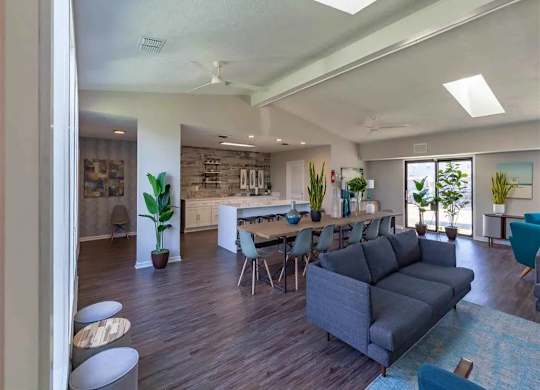 A living room with a grey couch and a dining table with chairs.