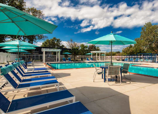 A sunny day at the pool with blue umbrellas and lounge chairs.