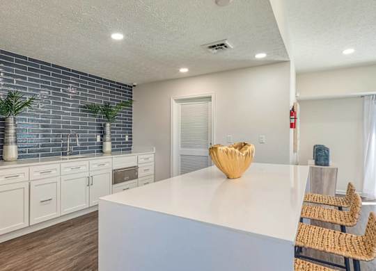 A kitchen with white cabinets and a blue backsplash.