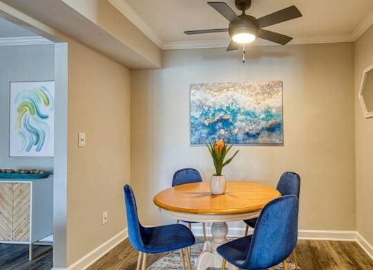 A dining room with a round table and blue chairs.