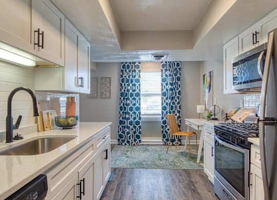 A kitchen with white cabinets and a black refrigerator.