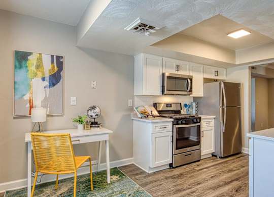 A kitchen with a yellow chair and a painting on the wall.