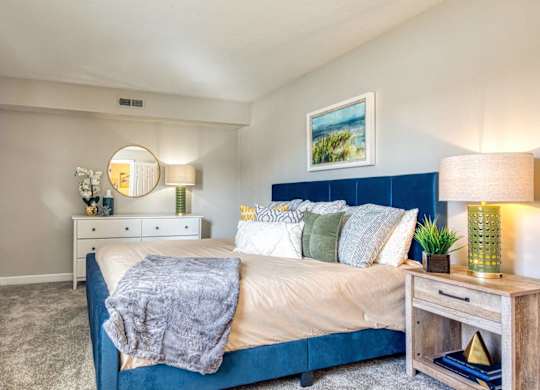 A bedroom with a bed, nightstand, and lamp.