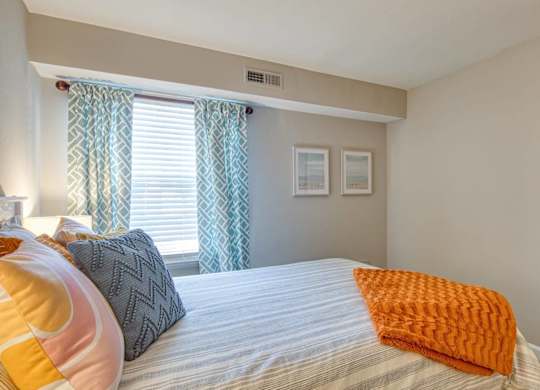 A bedroom with a bed, pillows, and a window with curtains.