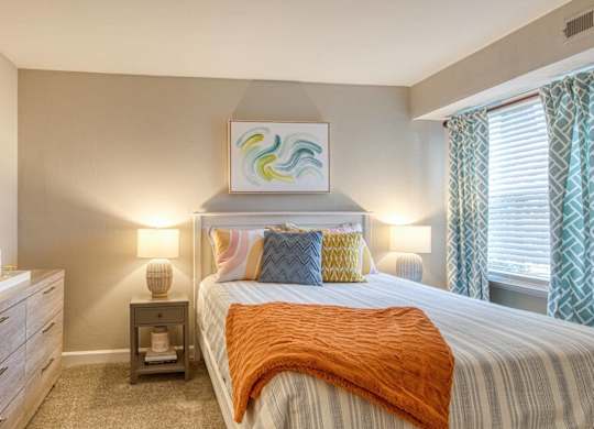 A bedroom with a bed, nightstand, and a mirror.