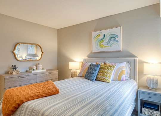 A bedroom with a bed, nightstand, and a painting on the wall.