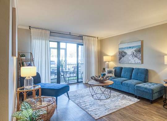 A living room with a blue sofa and a large window.