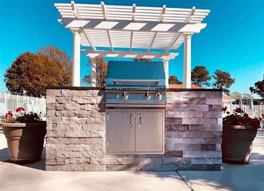 An outdoor kitchen with a grill and sink.