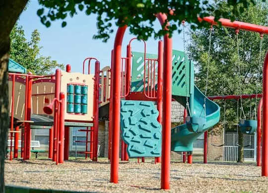 A playground with a red frame and a green slide.