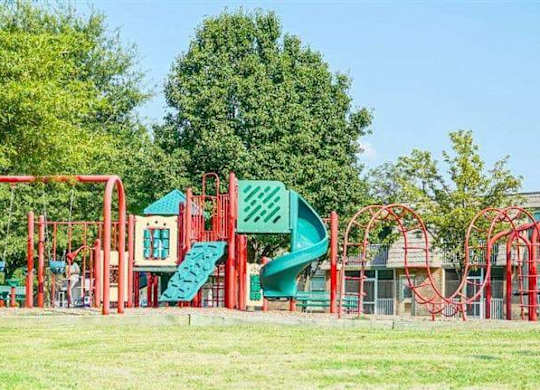 A playground with a red and green slide and a red and green structure.