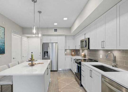 a kitchen with white cabinets and stainless steel appliances at Mayla Pompano, Pompano Beach, 33062