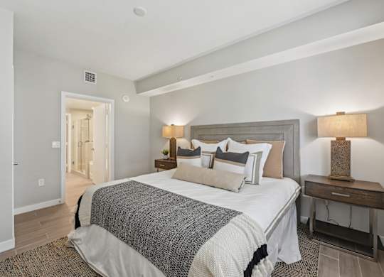 A bedroom with a large bed and a nightstand with a lamp.