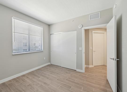 A room with a white door and a window with blinds.