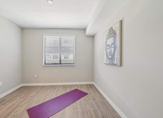 A yoga mat is on the floor of a room with a picture of Buddha on the wall.