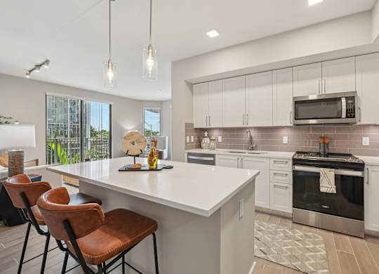 A modern kitchen with white countertops and brown leather chairs.