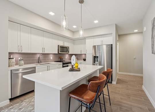 A modern kitchen with a white island and stainless steel appliances.