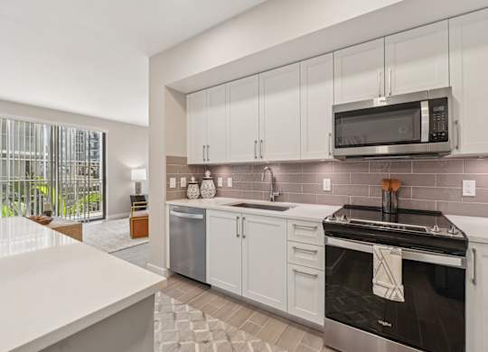 A modern kitchen with a stainless steel oven and white cabinets.