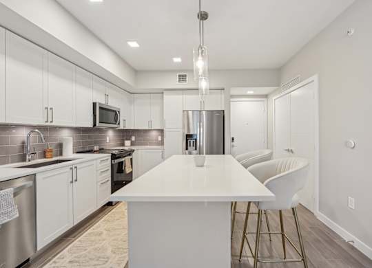 A modern kitchen with a white island and stainless steel appliances.