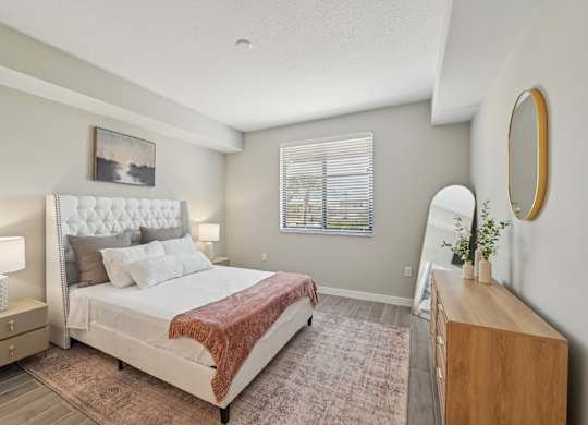 A bedroom with a large bed and a wooden dresser.