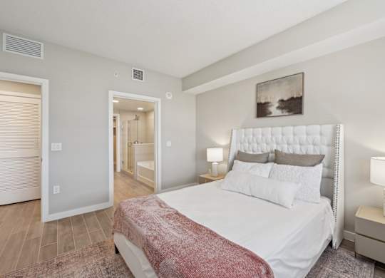 A bedroom with a large bed and a painting on the wall.