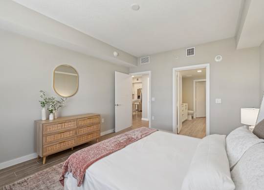 A bedroom with a bed, dresser, and mirror.