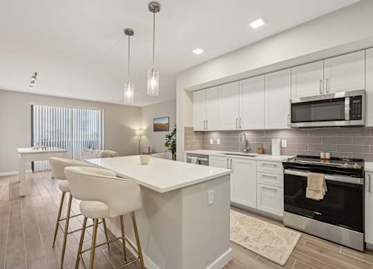 A modern kitchen with a white island and bar stools.