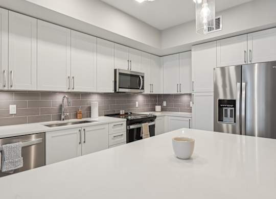A modern kitchen with a white countertop and stainless steel appliances.