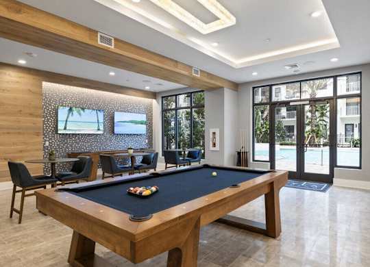 a pool table in a room with a tv and chairs at Mayla Pompano, Pompano Beach, FL
