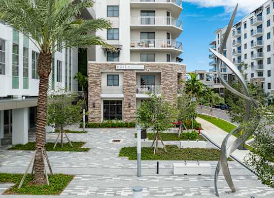 A modern building with a courtyard and palm trees.