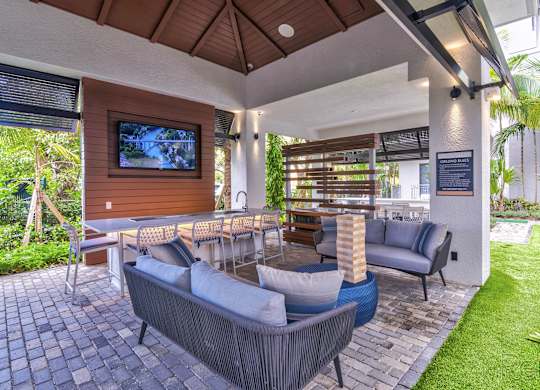 A patio with a grey couch and a wooden television at Mayla Pompano, Pompano Beach, 33062