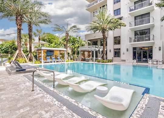 A pool with sun loungers and a building at Mayla Pompano, Pompano Beach