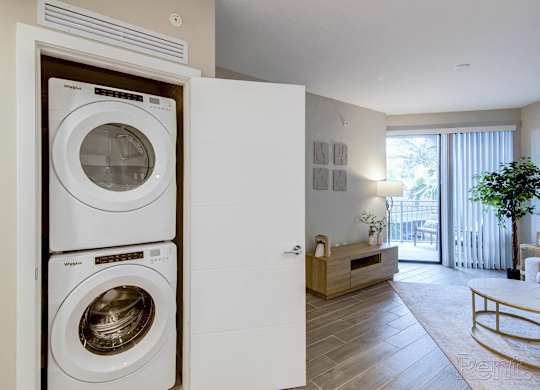 A white washing machine is in a cabinet in a room with a wooden floor.