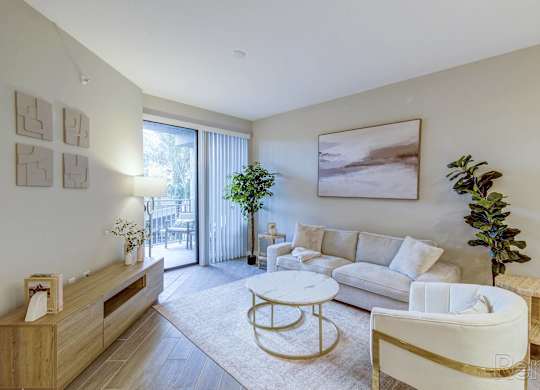 A living room with a white couch, a coffee table, and a potted plant.