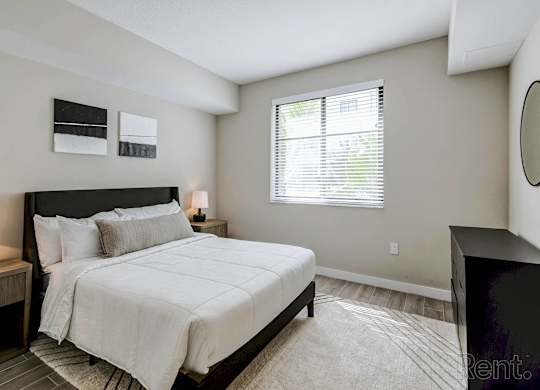 A bedroom with a large bed and a window with blinds.
