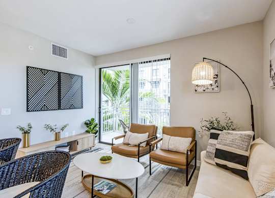 A living room with a white couch, a coffee table, and a large window.