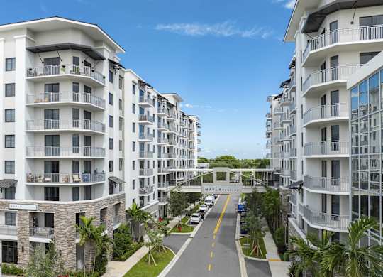 A street view of a residential area with apartment buildings on both sides at Mayla Pompano, Pompano Beach, FL