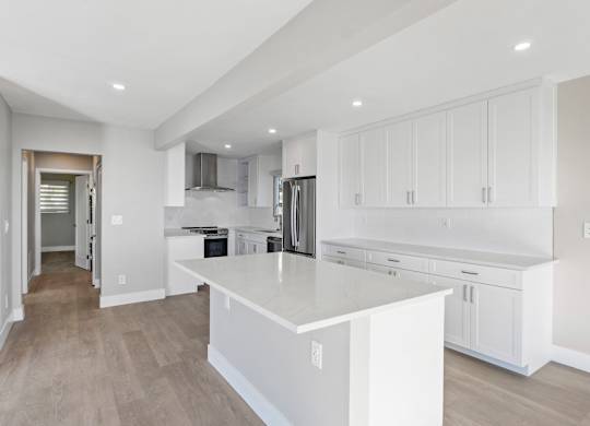 A modern kitchen with white cabinets and a large island.at Ocean Edge @ Laguna Beach, Laguna Beach, CA