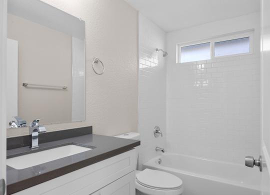A white bathroom with a toilet, sink, and bathtub.