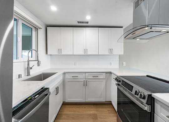 A modern kitchen with white cabinets and stainless steel appliances.
