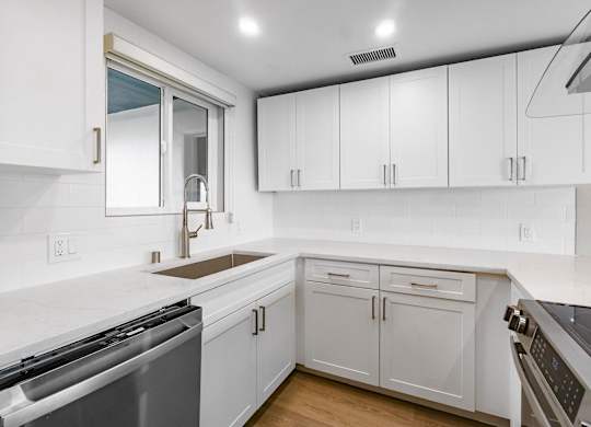 A modern kitchen with white cabinets and stainless steel appliances.