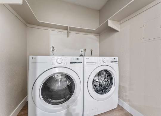 Two white front loading washing machines in a laundry room.