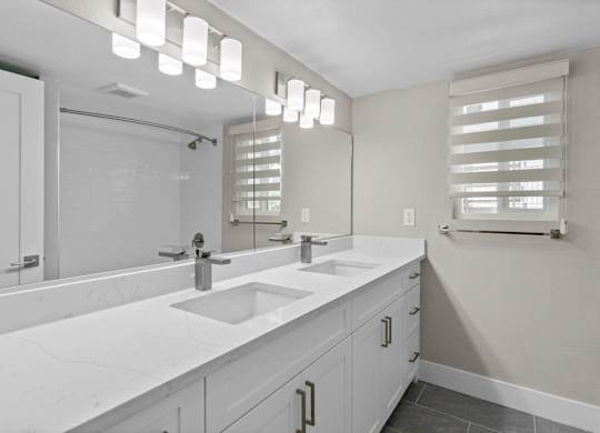 A bathroom with a white countertop and a large mirror.