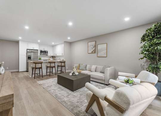A modern living room with a kitchen in the background at Tamarack Sands Apartment Homes, Carlsbad, CA
