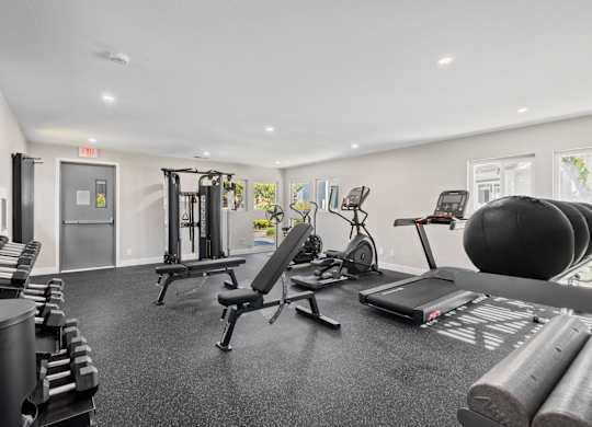 A gym with a variety of equipment including weights, a treadmill, and a stationary bike.